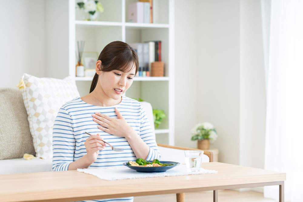 胸やけをして食事が喉を通らない女性