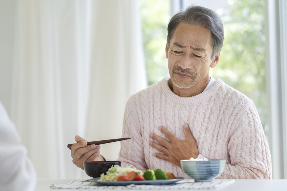 胸やけをして食事が喉を通らない男性