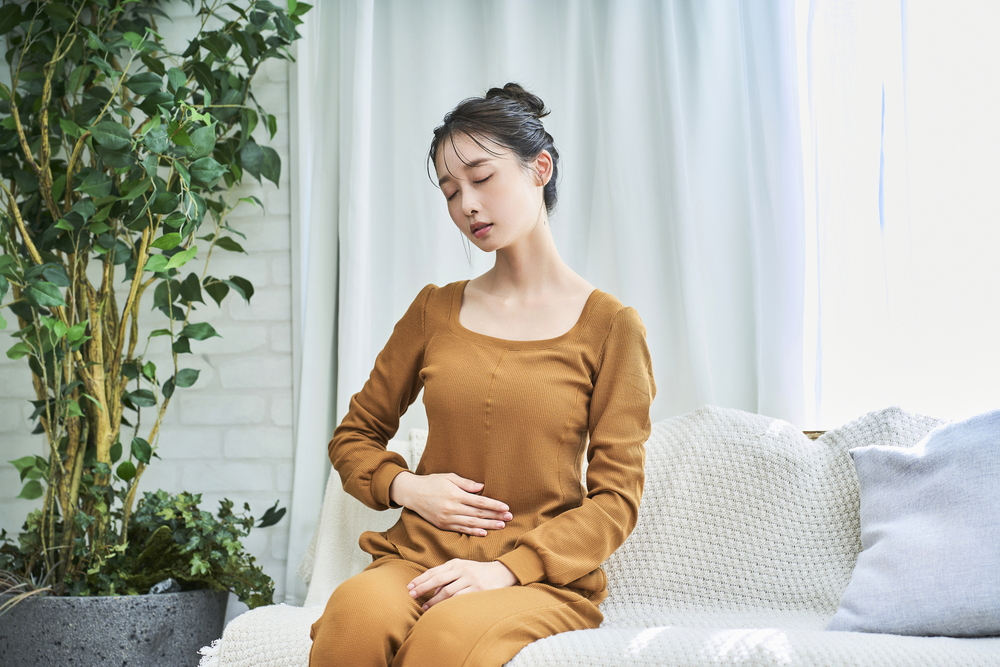 座って胃をおさえている女性